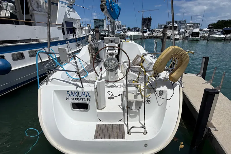 Slide: The Image of 2006 Beneteau Oceanis Clipper 323 sailboat docked, featuring a spacious cockpit and steering wheel. - 31