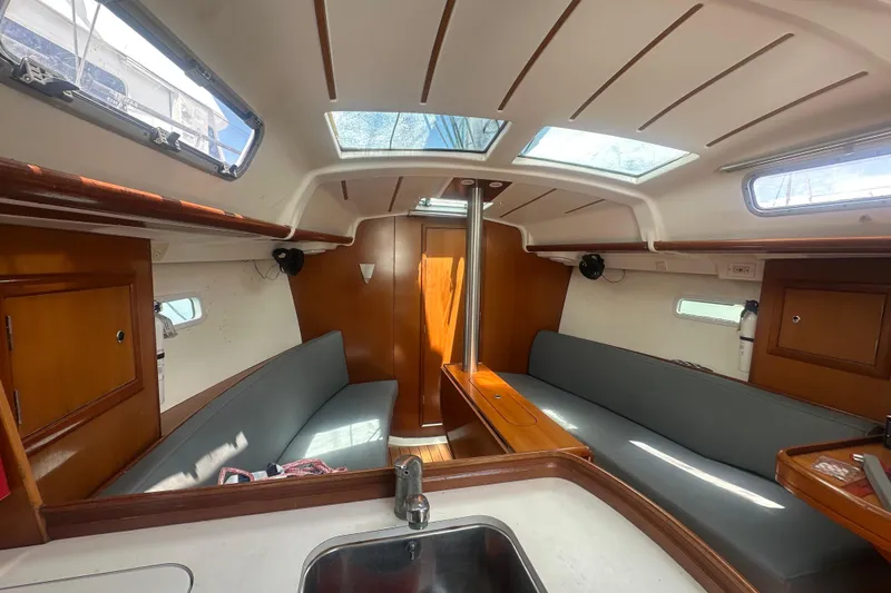 Slide: The Image of Interior of 2006 Beneteau Oceanis Clipper 323 sailboat, featuring cozy seating and wooden finishes. - 61