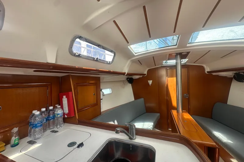 Slide: The Image of Interior of 2006 Beneteau Oceanis Clipper 323 sailboat, featuring cozy seating and kitchenette. - 62