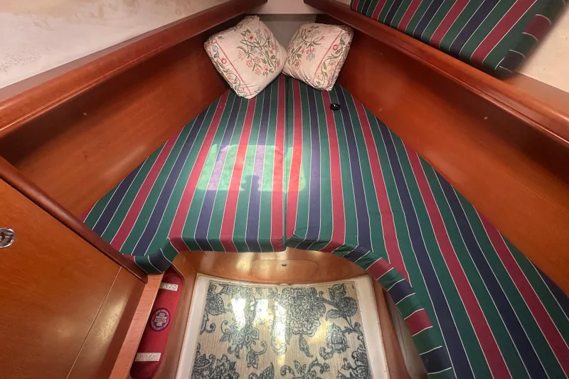 Slide: The Image of Cozy cabin interior of 2006 Beneteau Oceanis Clipper 323 with striped bedding and floral pillows. - 68