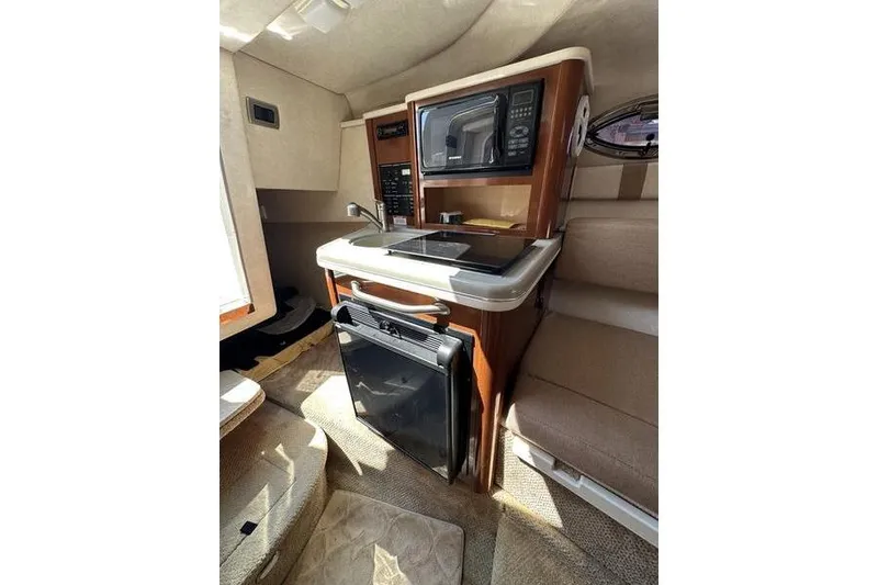 Slide: The Image of Interior of 2010 Sea Ray 240 Sundancer boat with kitchenette and seating area. - 22