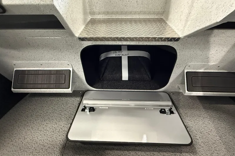 Slide: The Image of Interior storage compartment of 2025 KingFisher Escape HT boat, featuring secure hatch and carpeted interior. - 26