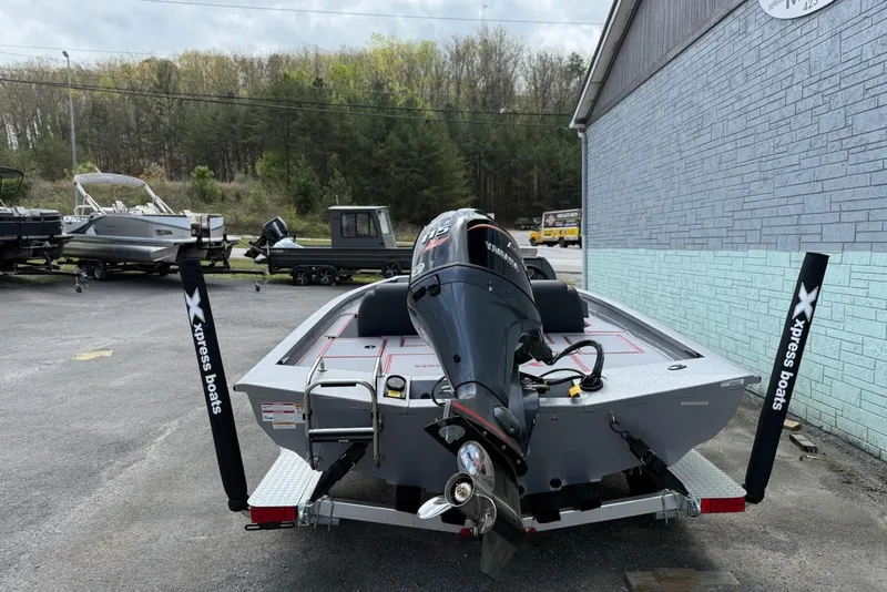 Slide: The Image of 2026 Xpress H18C Crappie boat with motor, parked outdoors near other boats. - 8