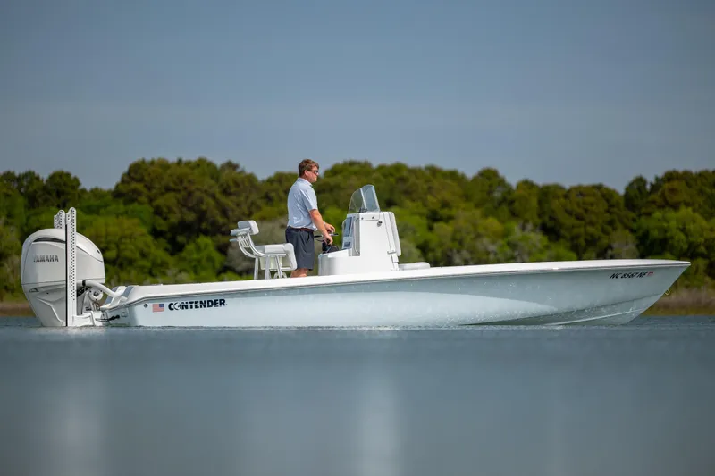 The Image of 2024 Contender 23 Bay boat on calm water with Yamaha engine, man steering. - 0