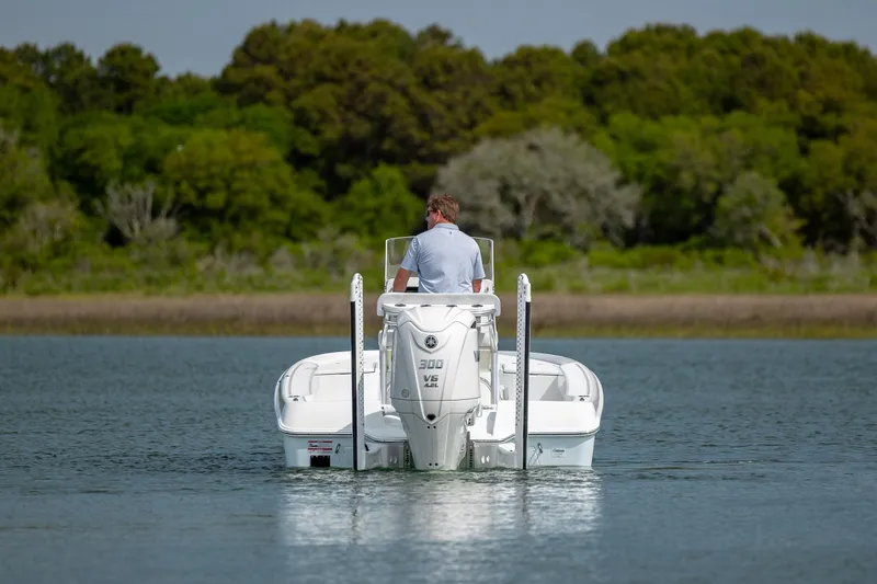 Slide: The Image of 2024 Contender 23 Bay boat cruising on a calm lake with lush green trees in the background. - 12