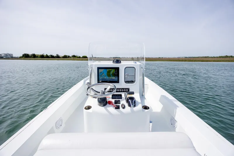 Slide: The Image of 2024 Contender 23 Bay boat dashboard with steering wheel and navigation system on open water. - 15