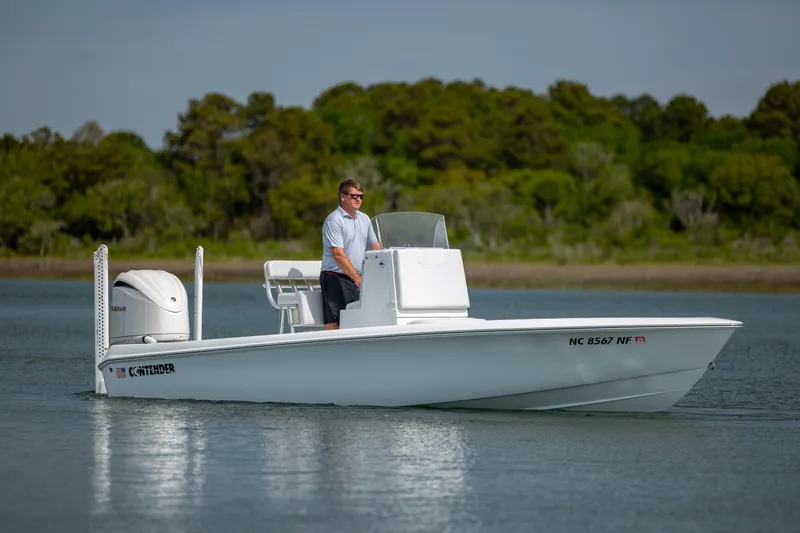 Slide: The Image of 2024 Contender 23 Bay boat cruising on calm water with lush green background. - 2