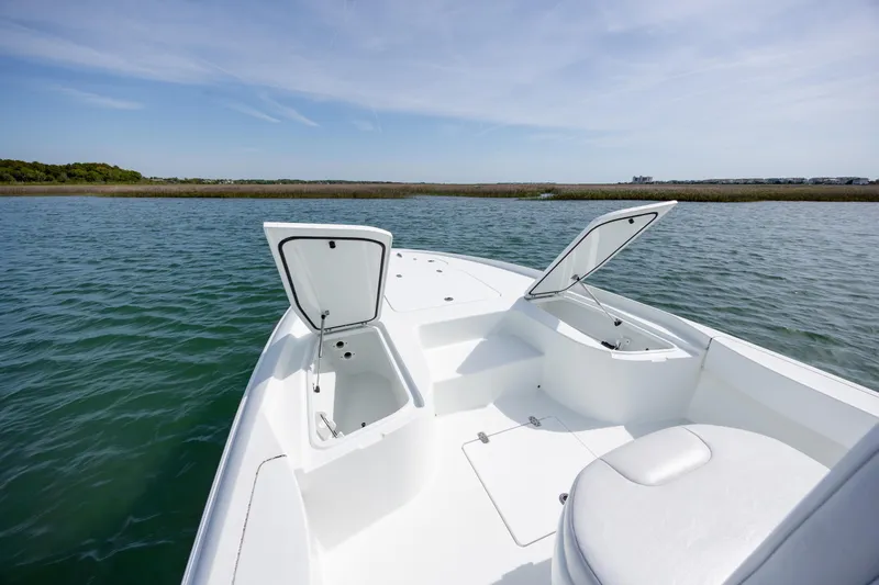 Slide: The Image of 2024 Contender 23 Bay boat with open storage compartments on calm water. - 27