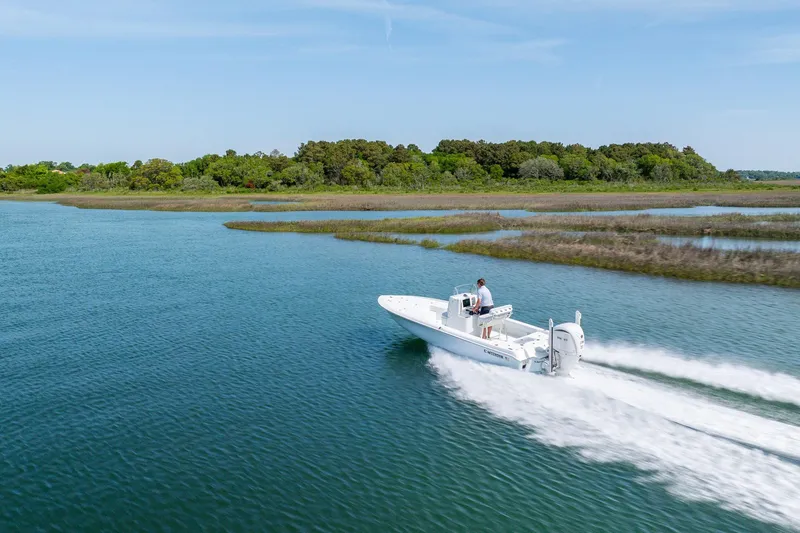 Slide: The Image of 2024 Contender 23 Bay boat cruising on a scenic waterway with lush greenery. - 38