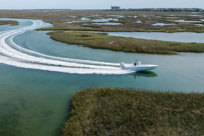 Slide: The Image of 2024 Contender 23 Bay boat cruising through scenic marshland waterways. - 39