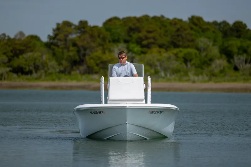 Slide: The Image of 2024 Contender 23 Bay boat cruising on calm water with lush green background. - 4