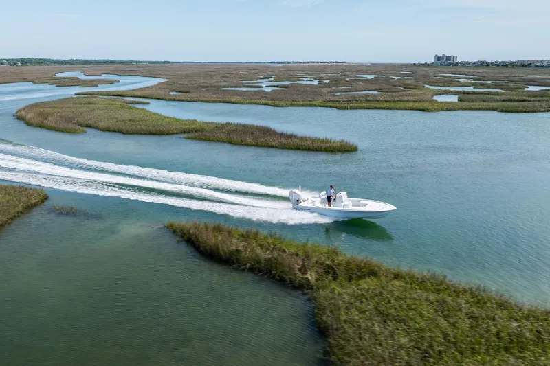 Slide: The Image of 2024 Contender 23 Bay boat cruising through scenic marshland waterways. - 40