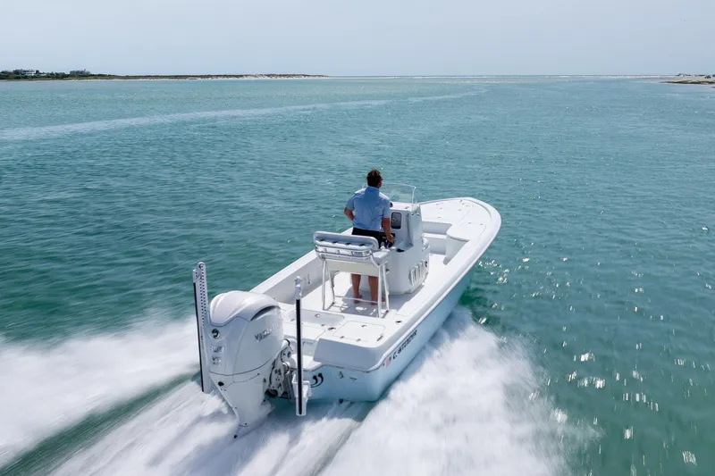 Slide: The Image of 2024 Contender 23 Bay boat cruising on open water, rear view. - 45