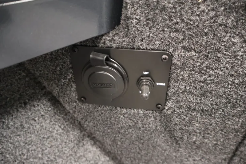 Slide: The Image of 2026 Crestliner 2050 Authority boat trim switch and outlet on carpeted panel. - 23