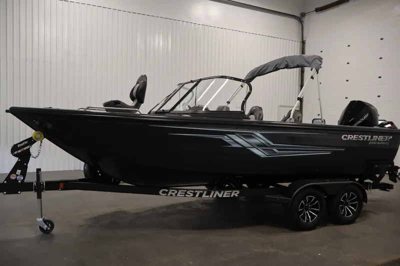 Slide: The Image of 2026 Crestliner 2050 Authority boat in showroom, black exterior, on a trailer. - 18