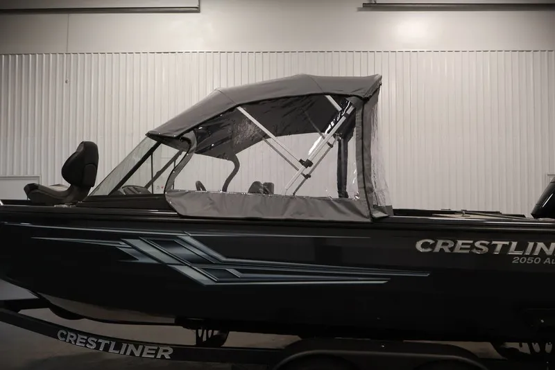 Slide: The Image of 2027 Crestliner 2050 Authority boat with canopy, displayed indoors on a trailer. - 54