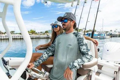 Slide: The Image of Couple enjoying a ride on a 2026 Tidewater 232 CC boat, sunny day, fishing rods visible. - 2