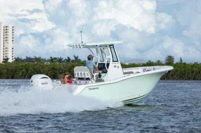 Slide: The Image of 2026 Tidewater 232 CC boat cruising on water with passengers, under a cloudy sky. - 3