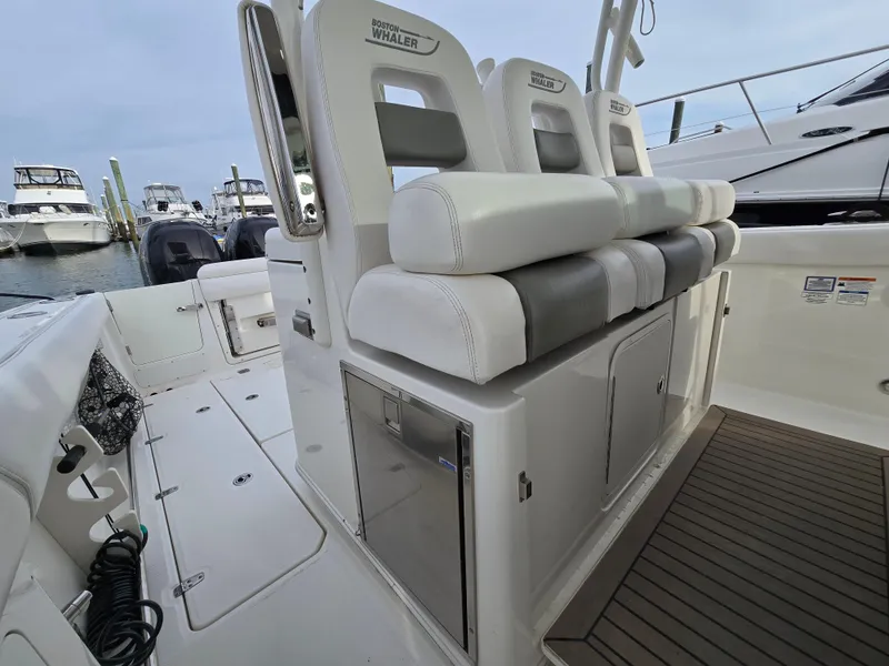 Slide: The Image of 2015 Boston Whaler 350 Outrage interior with cushioned seating and storage, docked at marina. - 13