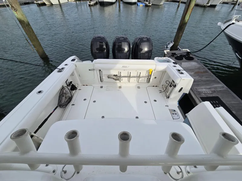 Slide: The Image of 2015 Boston Whaler 350 Outrage boat docked, featuring spacious deck and triple outboard engines. - 14