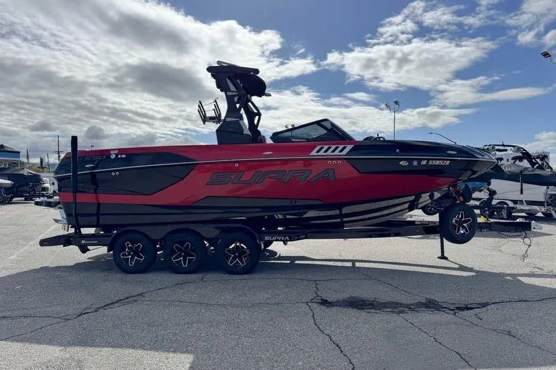 Slide: The Image of 2022 Supra SE boat in red and black on a trailer under a cloudy sky. - 10