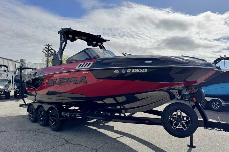 Slide: The Image of 2022 Supra SE boat in red and black on a trailer under a cloudy sky. - 4