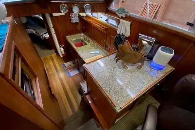 Slide: The Image of Interior of a 1977 Uniflite 42 Convertible yacht with a granite countertop and wooden cabinetry. - 10