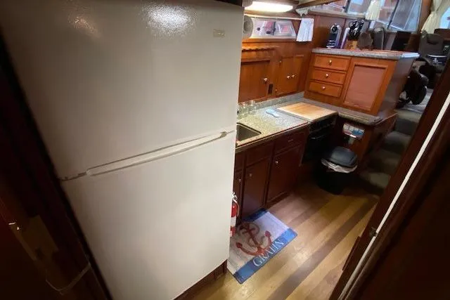 Slide: The Image of 1977 Uniflite 42 Convertible yacht kitchen with wooden cabinets and white refrigerator. - 12