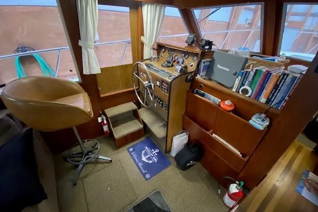 Slide: The Image of 1977 Uniflite 42 Convertible boat interior with helm, bookshelves, and nautical decor. - 9