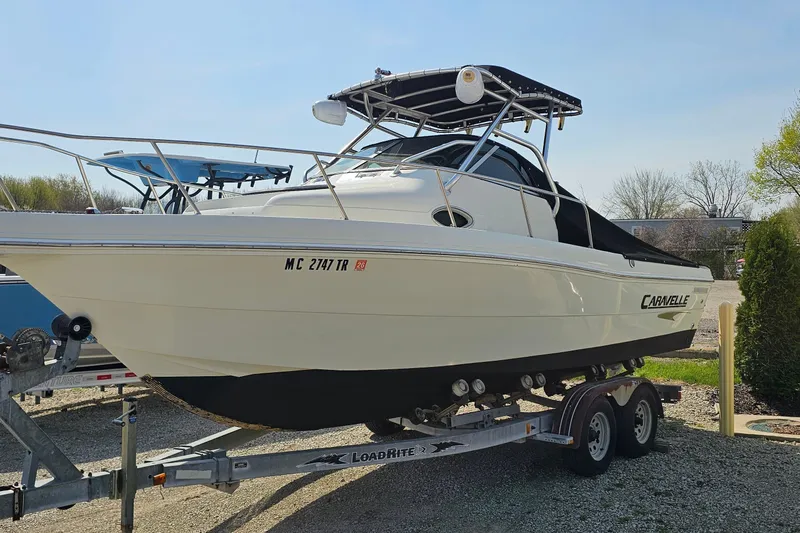 The Image of 2003 Caravelle 230 Walk Around Stern Drive boat on trailer, parked outdoors. - 1