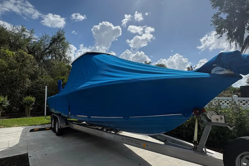 Slide: The Image of 2019 Blue Wave 2800 Pure Hybrid boat covered on trailer under blue sky. - 23