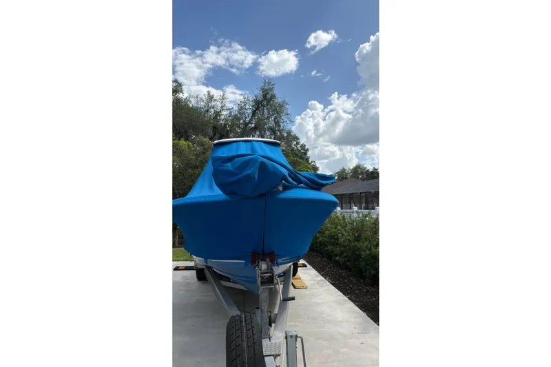 Slide: The Image of 2019 Blue Wave 2800 Pure Hybrid boat covered, parked on a trailer under a blue sky. - 24