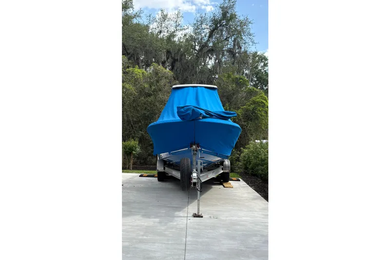 Slide: The Image of 2019 Blue Wave 2800 Pure Hybrid boat covered in blue tarp on trailer. - 25