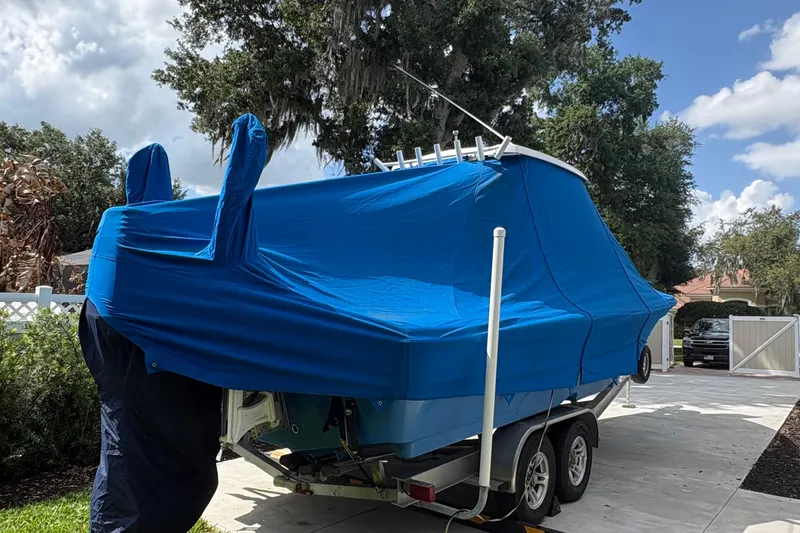 Slide: The Image of 2019 Blue Wave 2800 Pure Hybrid boat covered with blue tarp on trailer. - 29