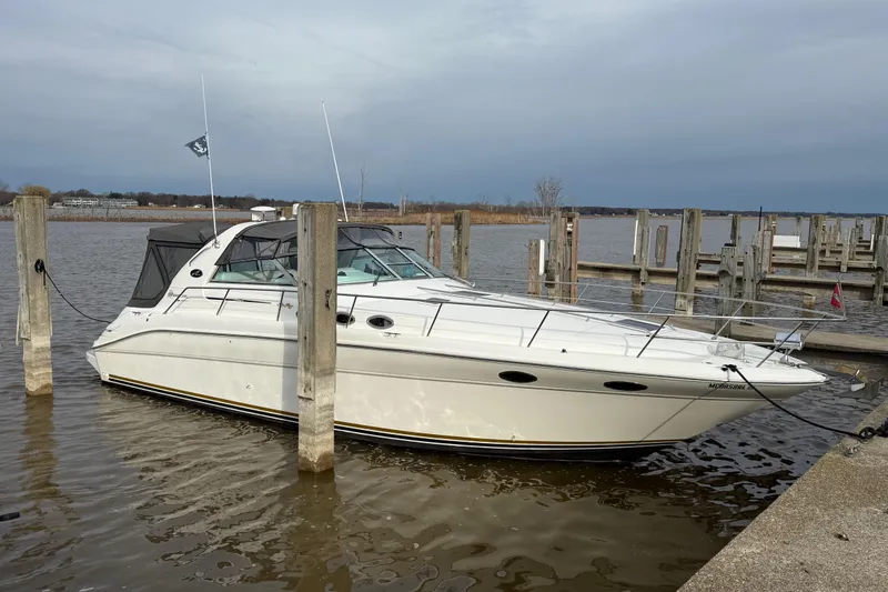Slide: The Image of 1995 Sea Ray Sundancer 370 docked at a marina, showcasing sleek design and white exterior. - 2
