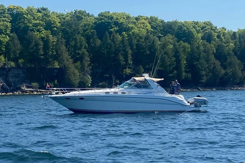 Slide: The Image of 1995 Sea Ray Sundancer 370 yacht on a serene lake with lush forest backdrop. - 25