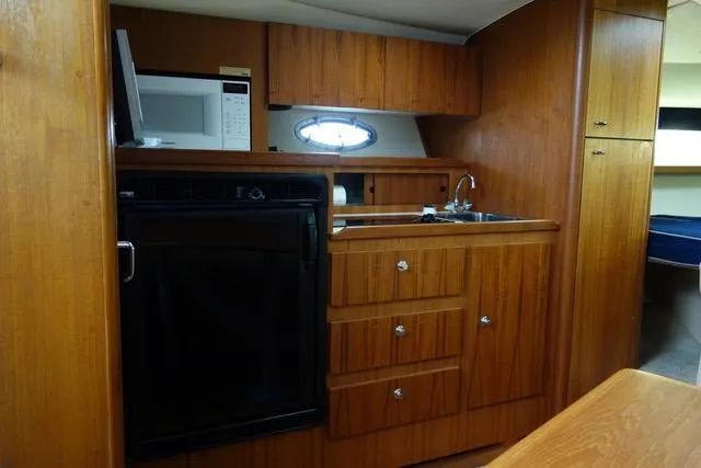 Slide: The Image of 2001 Tiara Yachts 3100 Open interior with wooden cabinetry and compact kitchen area. - 10
