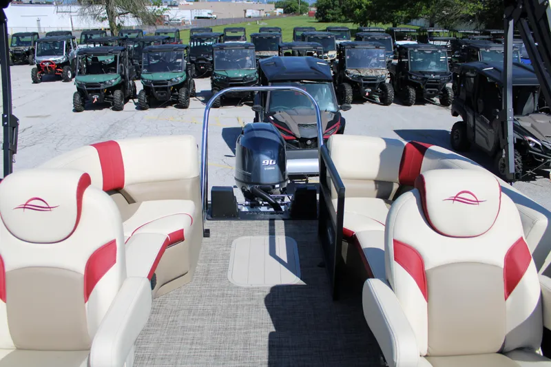 Slide: The Image of 2025 SunCatcher Select 20RC pontoon boat interior with red and white seating, parked outdoors. - 9