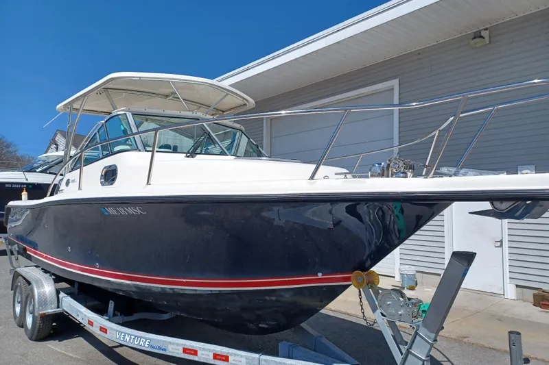 The Image of 2013 Pursuit OS 255 Offshore boat on trailer, parked near a building. - 0