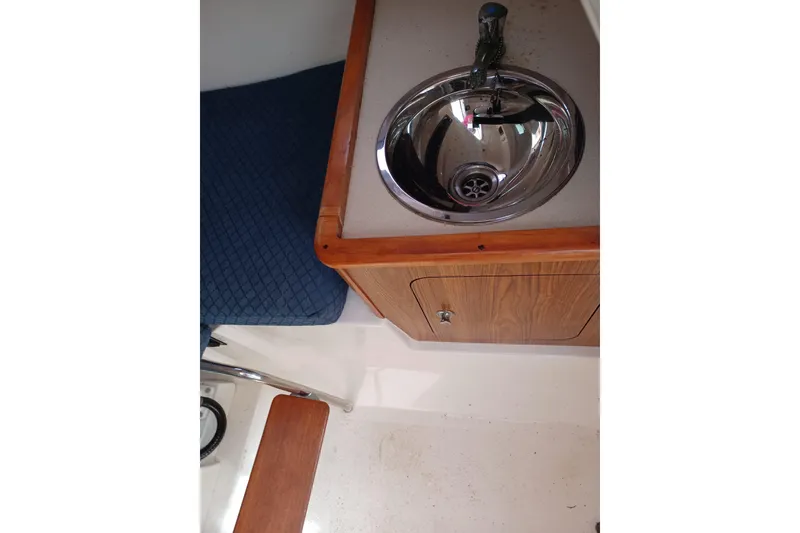 Slide: The Image of 2013 Pursuit OS 255 Offshore boat interior with sink and wooden cabinetry. - 13