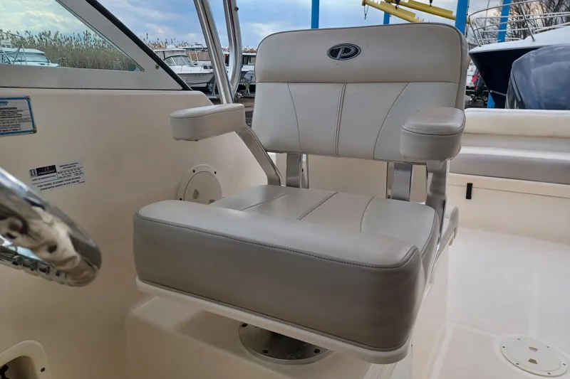 Slide: The Image of Captain's chair on 2013 Pursuit OS 255 Offshore boat, featuring comfortable seating and armrests. - 17
