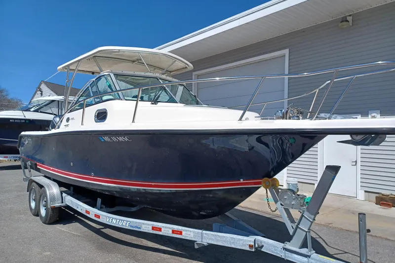 Slide: The Image of 2013 Pursuit OS 255 Offshore boat on trailer, parked outside a building. - 3