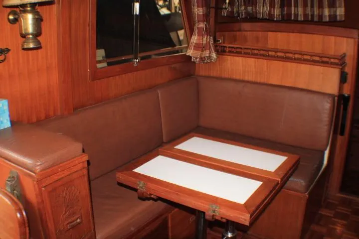Slide: The Image of 1977 CHB Double Cabin interior with brown seating and foldable wooden table. - 25