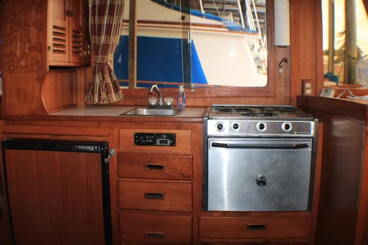 Slide: The Image of 1977 CHB Double Cabin kitchen with wooden cabinetry, stove, sink, and refrigerator. - 28