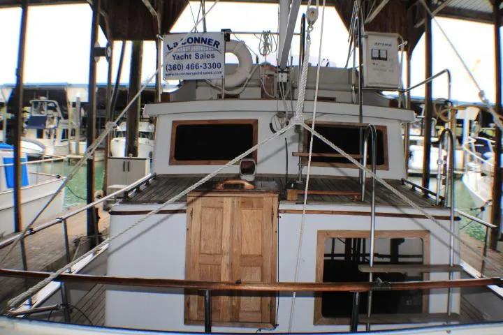 Slide: The Image of 1977 CHB Double Cabin yacht docked, featuring wooden doors and deck, with yacht sales sign. - 4