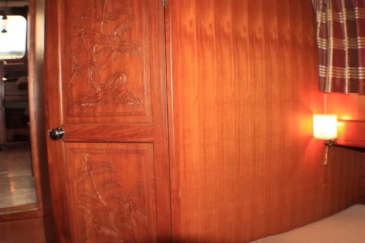 Slide: The Image of Wood-paneled cabin interior of a 1977 CHB Double Cabin boat, featuring carved door and wall lamp. - 48