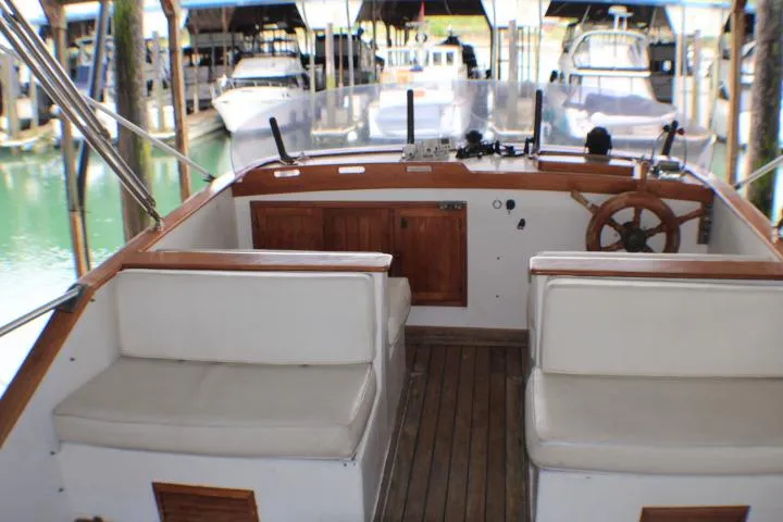 Slide: The Image of 1977 CHB Double Cabin boat interior with wooden steering wheel and white seating. - 8