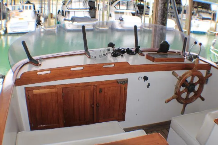 Slide: The Image of 1977 CHB Double Cabin boat helm with wooden wheel and marina background. - 9