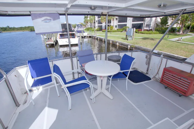 Slide: The Image of 1984 Present Yachts 42 Sundeck with outdoor seating, docked by a serene waterfront. - 26