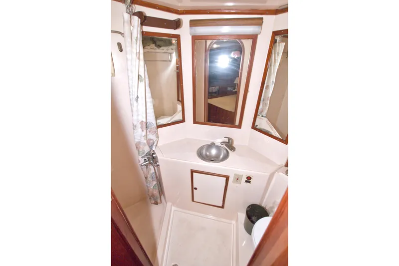 Slide: The Image of Compact bathroom in 1984 Present Yachts 42 Sundeck, featuring sink, mirrors, and shower area. - 60